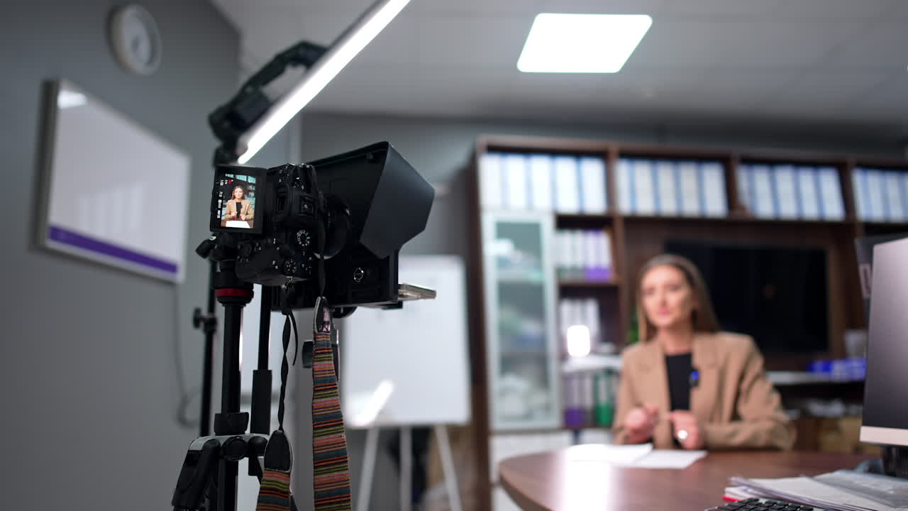Modern Caucasian blogger recording a video on professional camera. Low angle view. Blogging or vlogging concept. Blurred backdrop.