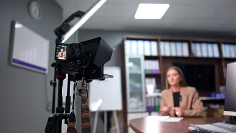 modern caucasian blogger recording a video on professional camera. low angle view. blogging or vlogging concept. blurred backdrop.