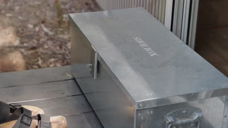 metal shoe box outside tiny cabin with person sliding shoes off to place inside