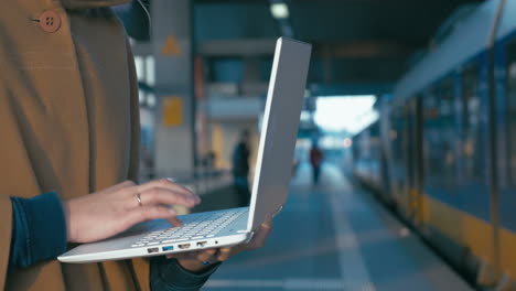 chica trabajando con una computadora portátil en la estación de tren