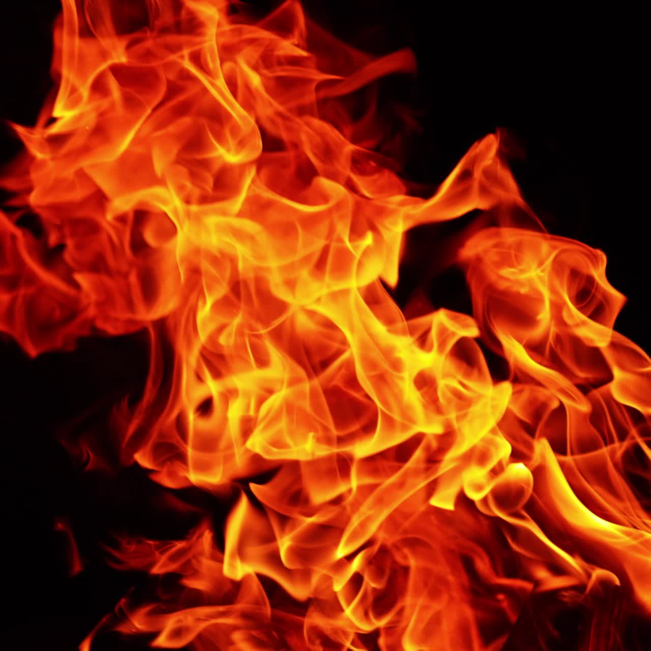 Glødende rød flamme fra bålet. Den øverste del af bålet er isoleret mod en sort baggrund. Tæt på