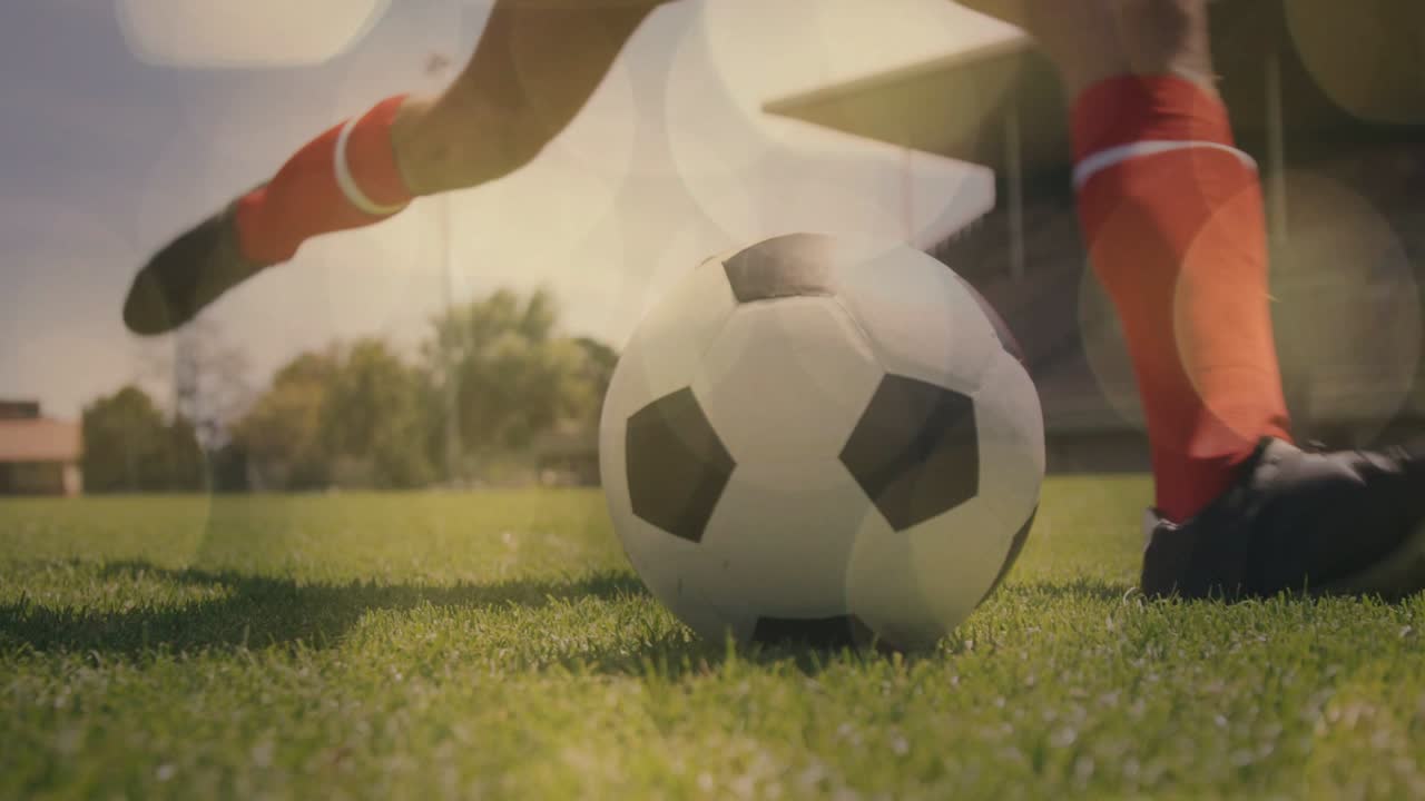 Fodboldspiller justerer holdning og tager tilløb, sparker bolden på græsset til sportstræning.