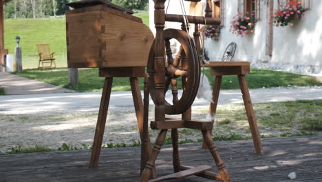 vintage wooden spinning wheel, traditional alpine house in background