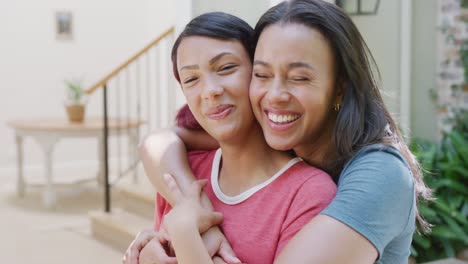 Portrait-of-happy-biracial-sisters-embracing-and-smiling-in-garden,-in-slow-motion