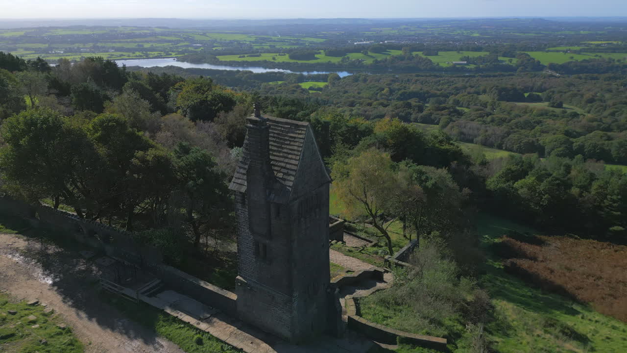 edificio de torre de piedra solitaria, vuelo lento sobre el estanque revelador y el campo más allá