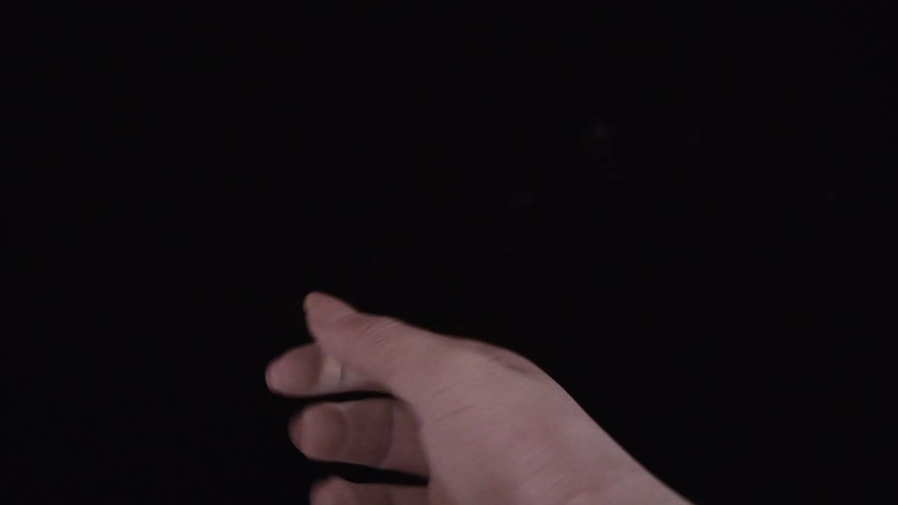 mujer joven pintada a mano con color blanco moviéndose suavemente en un fondo negro