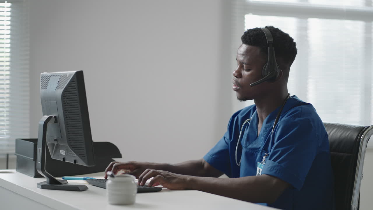 Afro-american male doctor or nurse with headset and computer working at hospital .young professional therapist doctor consulting customer client using remote communication speaking on webcam