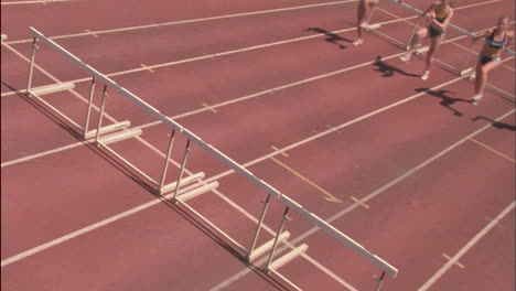 Female runners jump over hurdles 1