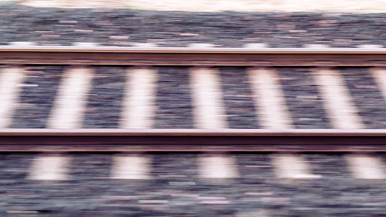 Binari ferroviari indiani che sfrecciano durante il viaggio su un treno in movimento con effetto mosso dovuto alla velocità, infrastruttura di trasporto