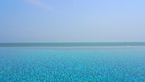 blue water of an infinity swimming pool with sea view on the horizon