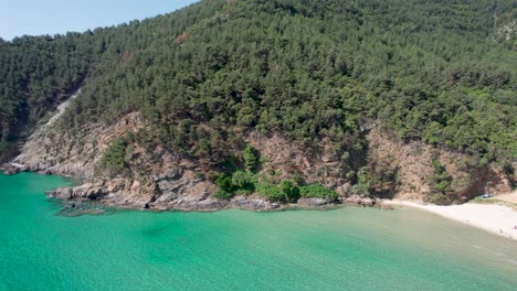 Vista-Aérea-De-La-Playa-Paraíso,-Rodeada-De-Vegetación-Verde-Y-Picos-De-Alta-Montaña-Con-Agua-Turquesa-Tropical,-Isla-De-Thassos,-Grecia,-Mar-Mediterráneo,-Europa