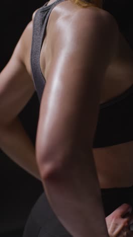 vertical video close up studio shot showing back of mature woman wearing gym fitness clothing doing stretching exercises