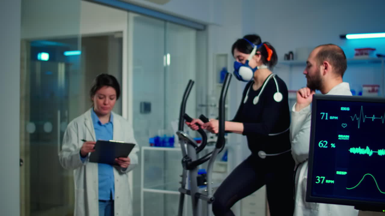 몸에 전극이 부착된 크로스 트레이너에서 마스크를 쓰고 달리는 운동선수