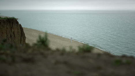 nature scene sandy coastline cloudy day. karate man training near ocean waves.