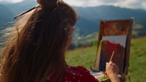 Back-view-woman-painter-drawing-on-easel-beautiful-mountains-landscape-close-up.