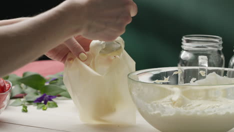 filling a piping bag with cream using a spoon