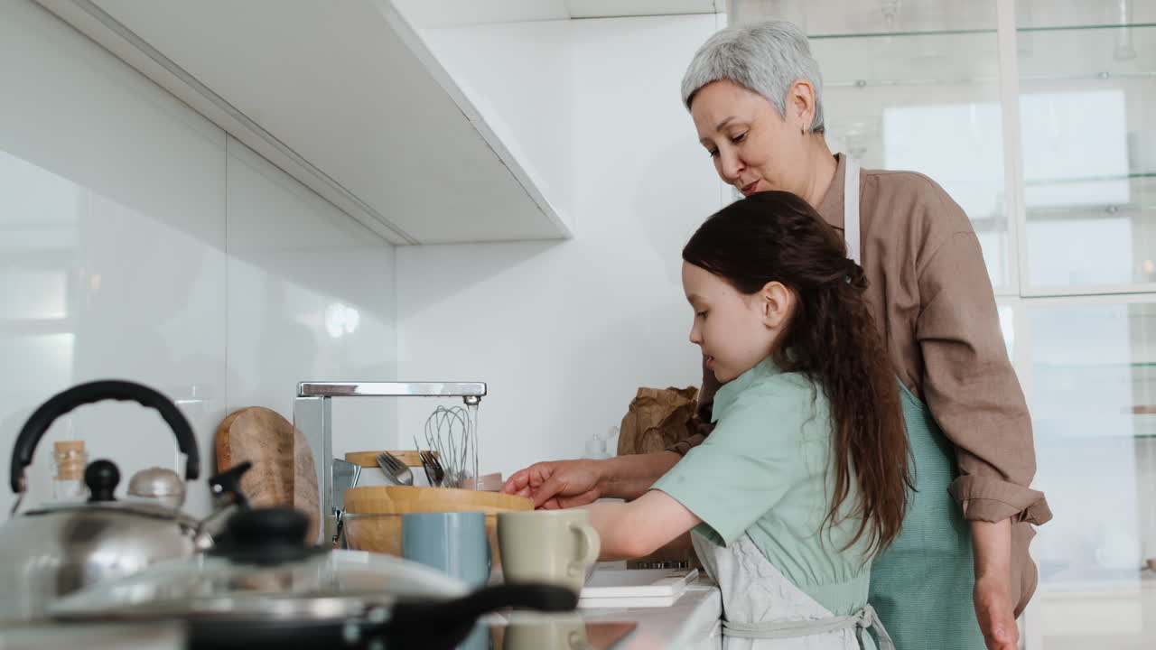 la abuela y la niña haciendo los platos