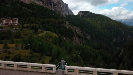 Presa-Del-Lago-Fedaia-En-La-Zona-Montañosa-De-Dolomita-Del-Norte-De-Italia-Con-Una-Persona-Admirando-La-Vista-Desde-La-Estructura-De-Barandilla-Cerca-De-Rifugio-Dolomia,-Vista-Aérea-De-Drones