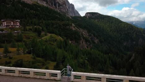 presa del lago fedaia en la zona montañosa de dolomita del norte de italia con una persona admirando la vista desde la estructura de barandilla cerca de rifugio dolomia, vista aérea de drones