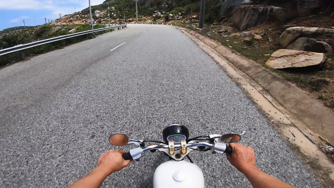 POV of man driving honda 67 motorcycle on empty coastal road at high speed