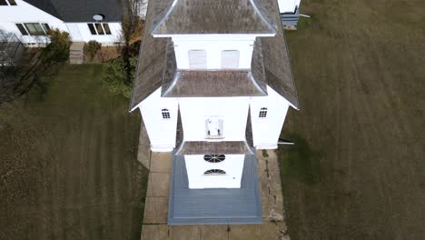 close up aerial shot of st boniface church in spring lake, canada. drone slowly ascending while keeping the beautiful white building in the middle of the frame. sunny autumn day with deep blue sky