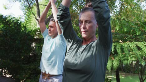 Pareja-Caucásica-Senior-Relajada-Feliz-Practicando-Yoga-Juntos-Sentados-En-El-Jardín