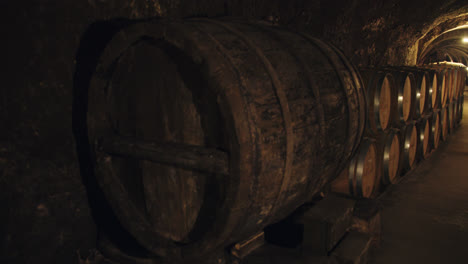 Wide-slow-motion-shot-of-the-interior-of-an-underground-winery-with-wine-barrels-in-Burgos,-Spain