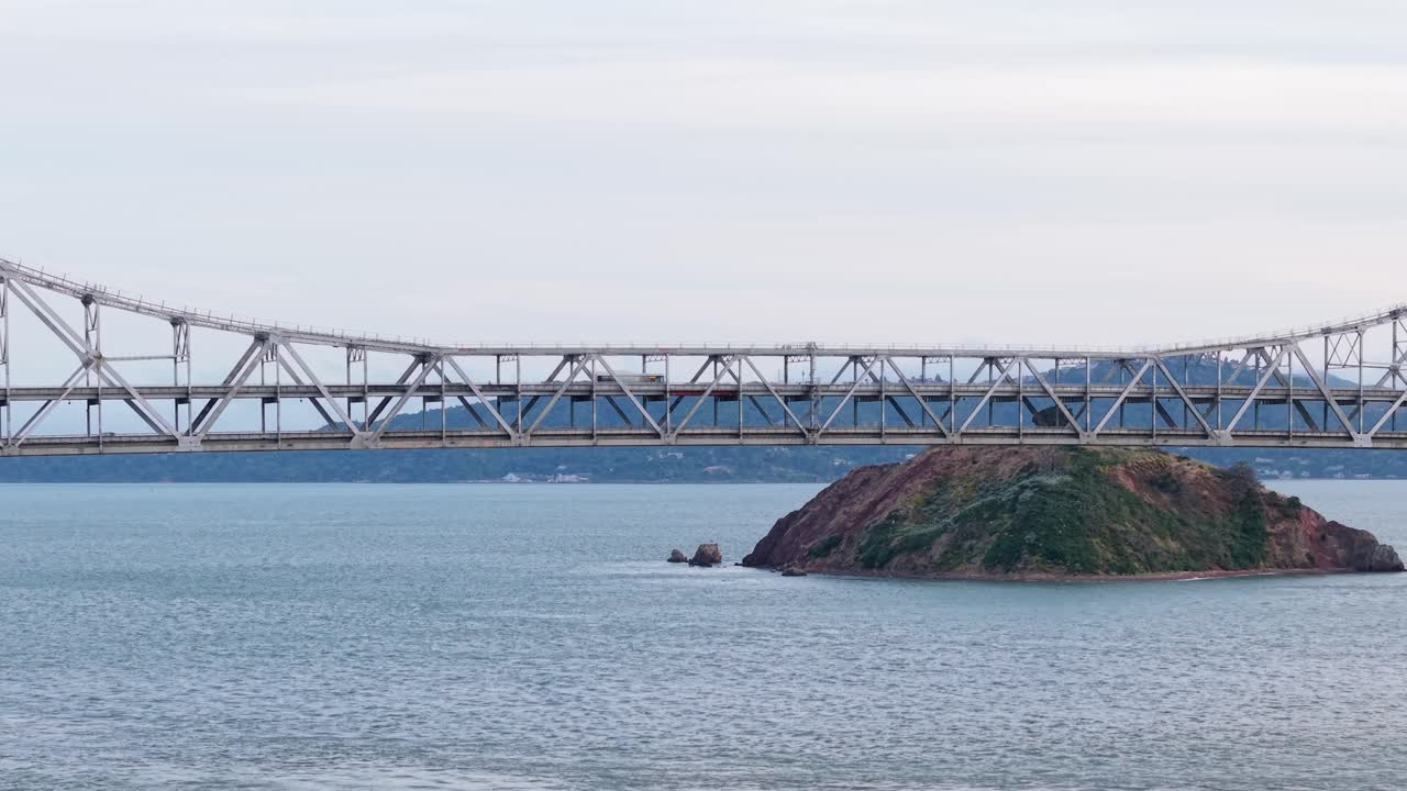 From the air, the bridge appears as a thread of movement across the bay, gently guiding traffic between two distant shores.