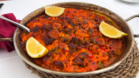 traditional spanish paella dish with chicken, vegetables and lemon slices in a restaurant, seafood in marbella spain, 4k shot