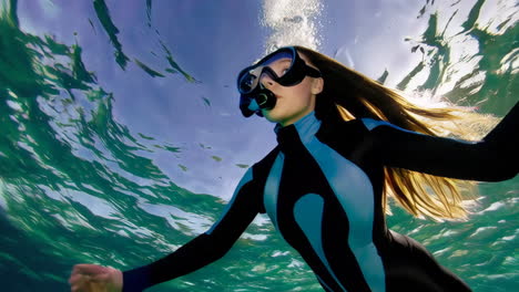 underwater adventure: woman snorkeling and freediving with sun rays