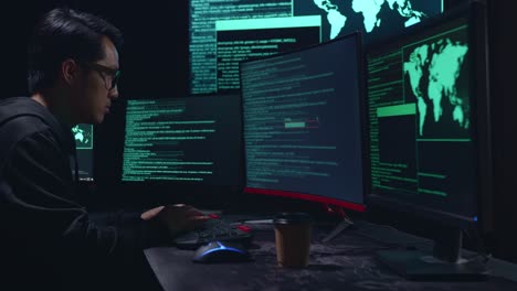 asian male hacker using multiple computer hacking and success downloading data