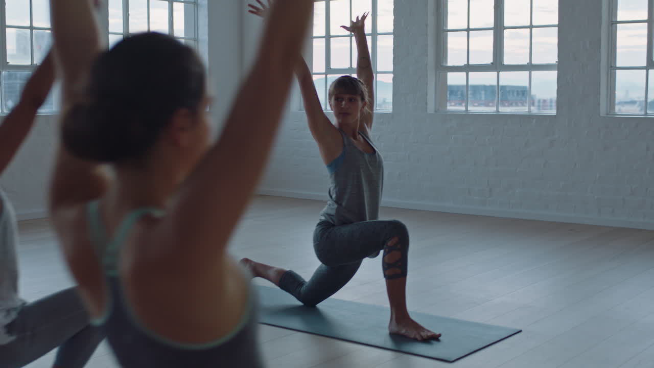 yoga class of healthy women practicing warrior pose enjoying exercising in fitness studio instructor leading group meditation teaching workout posture at sunrise