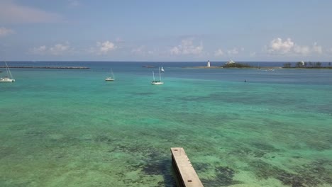 aerial view over a beach towards boats on the coast of nassau, bahamas - low, drone shot