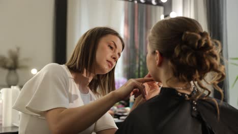 talented makeup artist meticulously applies makeup to a beautiful client in a modern studio setting