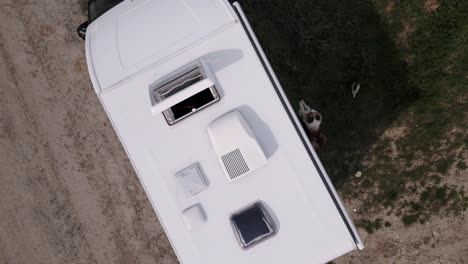 a person places a foldable portable solar panel on the roof of a caravan through the sunroof