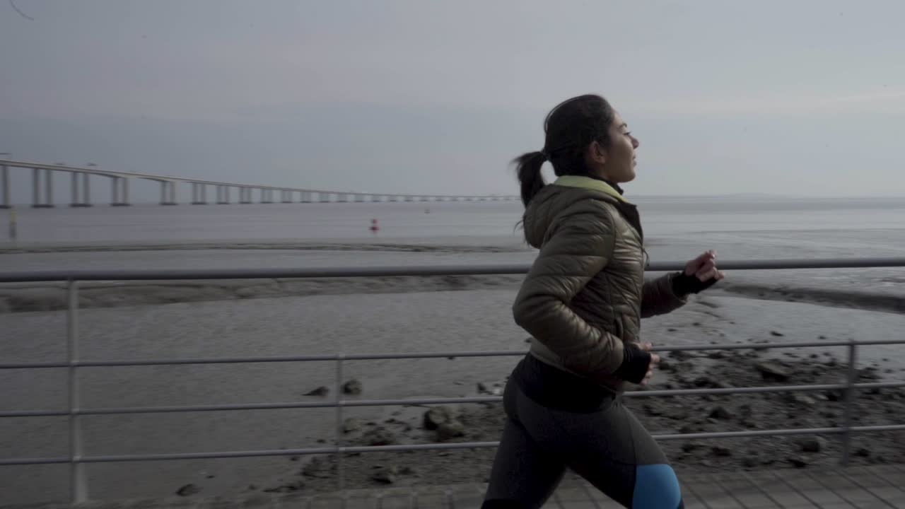una joven hindú sonriente corriendo por el muelle de la costa