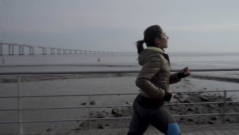 smiling young hindu woman running on seaside pier