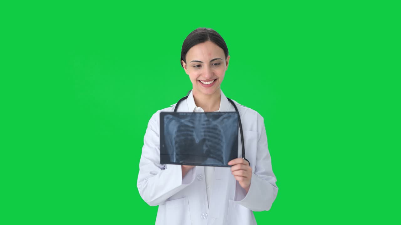Happy Indian female doctor checking X ray Green screen