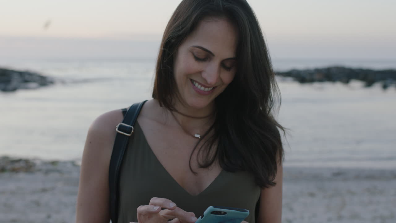 ritratto di una bella donna elegante che invia messaggi usando uno smartphone su una bella spiaggia tranquilla