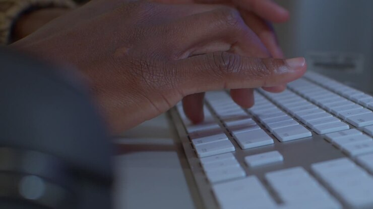 Developer fingers typing on mac keyboard with mouse on the right - medium shot