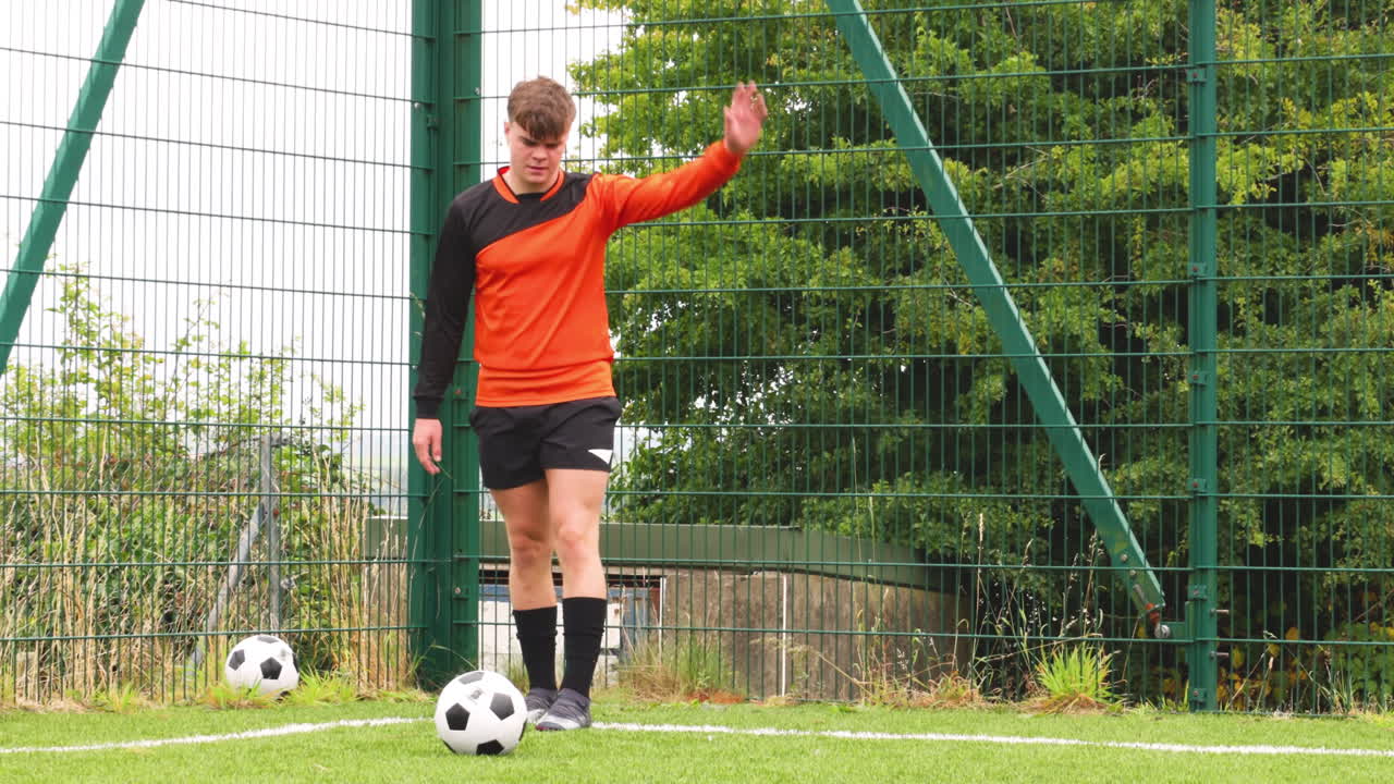 Soccer player in orange jersey walking on field, focused and determined