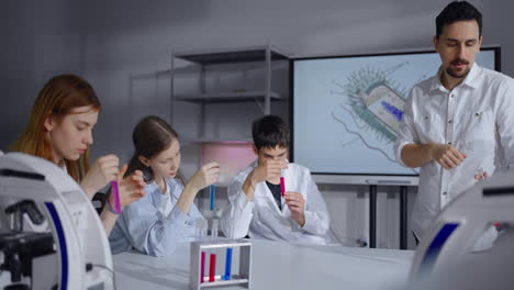 students and their teacher conduct a science experiment in a laboratory