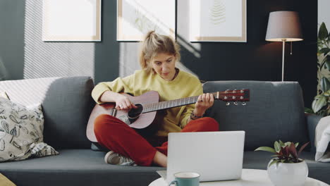 woman learning guitar online at home