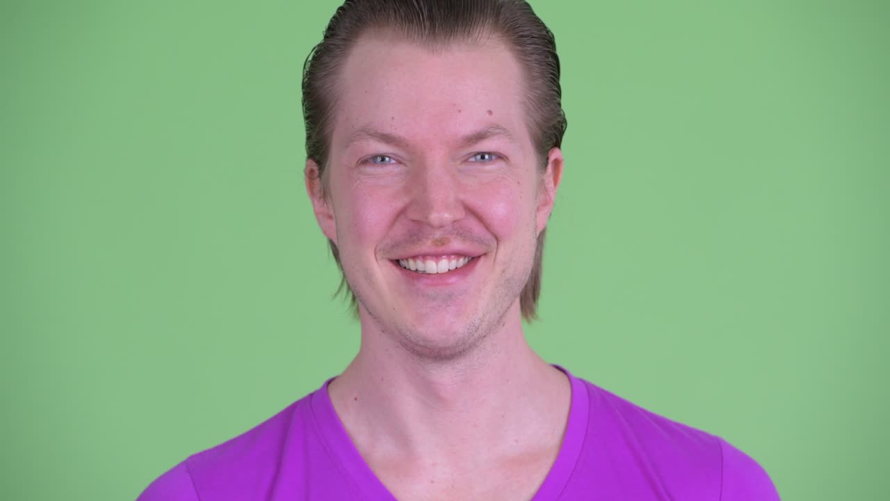fotografía de estudio de un joven sonriendo contra un fondo verde