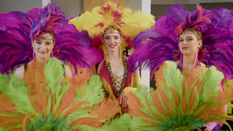 showgirls with feather fans looking and smiling to the camera