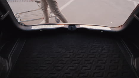 woman puts shopping bags in the trunk of a car