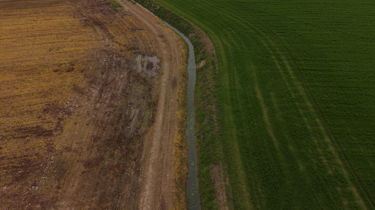Veduta aerea di un canale di irrigazione che attraversa campi agricoli in Lombardia, Italia, supportando la crescita delle colture e la distribuzione dell'acqua in terreni fertili