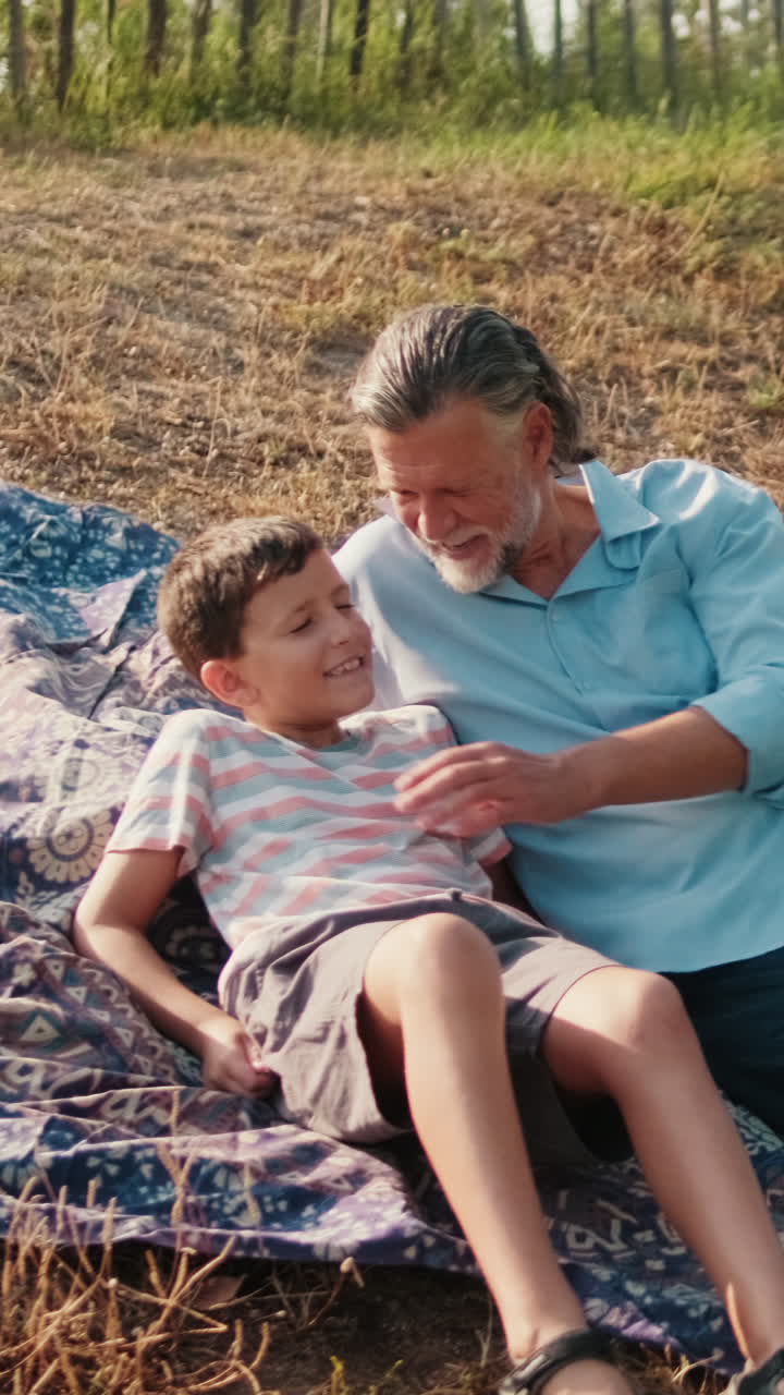 Nonno e nipote felici parlano all'aperto su una coperta