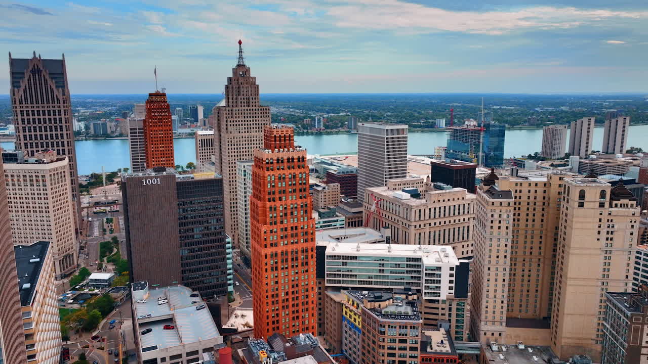 Flight at the tops of the high-rises in the downtown of Detroit, Michigan, USA. The Detroit River at backdrop. City view from drone at dusk time