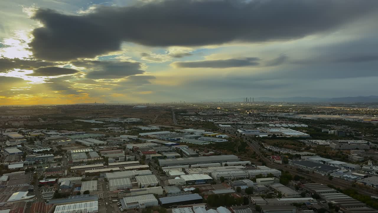 Elevated left side view of Madrid city at sunrise, under a colorful golden sky with few clouds. Footagtaken from a jet cockpit